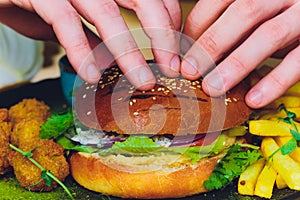 Vegetarian lentil burger in wholewheat bun with lettuce, tomato and cucumber accompanied by French fries Selective Focus