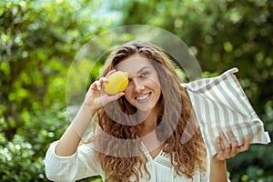Long -haired wowan in white shirt holding a lemon and smiling photo