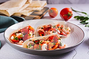 Vegetarian mini tacos with tomatoes, shrimp and herbs on a plate on the table