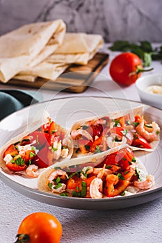 Vegetarian mini tacos with tomatoes, shrimp and herbs on a plate on the table vertical view