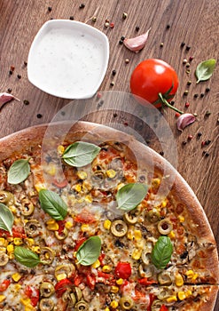 Vegetarian pizza and ingredients with spices on rustic wooden background, fast food