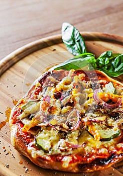 Vegetarian pizza with Mozzarella cheese, grilled zucchini, mushrooms, red onion, pepper and fresh basil. Italian pizza on wooden t