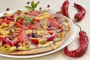 Vegetarian pizza with tomatoes, bell pepper, onion, green olives, cheese and spices on white background close up
