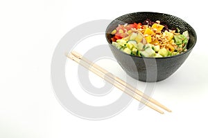 Vegetarian poke bowl in design black bowl with chopsticks below, isolated on white background. Green cucumber, red pepper, peanuts