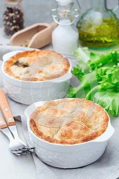 Vegetarian pot pie with lentil, mushroom, potato, carrot and green peas, covered with puff pastry, in baking dish, vertical