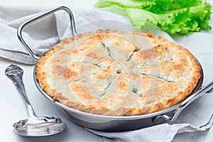 Vegetarian pot pie with lentil, mushrooms, potato, carrot and green peas, covered with puff pastry, in baking dish, horizontal