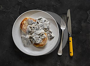 Vegetarian potato patties with creamy mushroom sauce on a dark background, top view