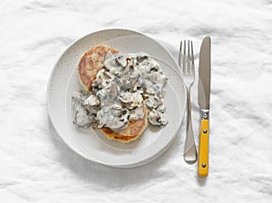 Vegetarian potato patties with creamy mushroom sauce on a light background, top view