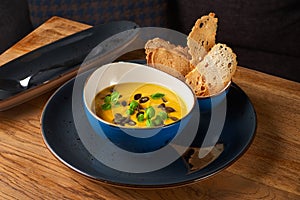 Vegetarian pumpkin cream soup in a white bowl decorated with seeds and herbs