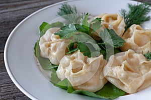 Vegetarian pumpkin mantas on a white plate, decorated with dill and parsley