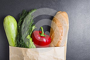 Vegetarian purchases at grocery store. Vegetables in paper bag on black background. Healthy food concept. Pack with vegetables