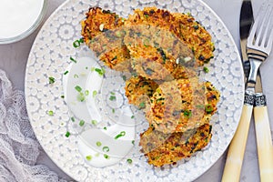 Vegetarian quinoa, carrot, coriander and green onion fritters served with yogurt on plate, horizontal, top view