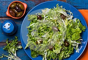 Vegetarian salad with lettuce and olives. Colorful blue orange background photo