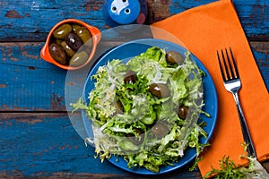 Vegetarian salad with lettuce and olives. Colorful blue orange background photo