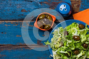 Vegetarian salad with lettuce and olives. Colorful blue orange background photo