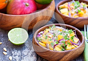 Vegetarian salad with mango oranges and red onion on the wooden