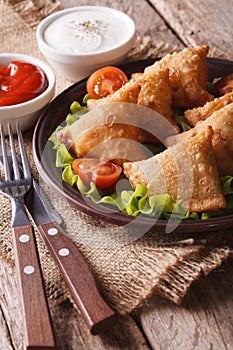 Vegetarian samosas on a plate with tomatoes and lettuce vertical