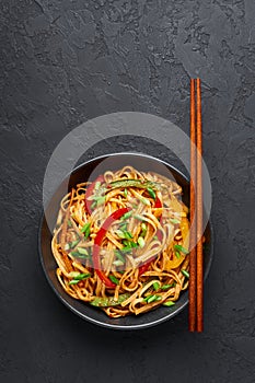 Vegetarian Schezwan Noodles or Vegetable Hakka Noodles or Chow Mein in black bowl at dark background. Indo-chinese cuisine hot