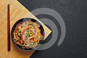 Vegetarian Schezwan Noodles or Vegetable Hakka Noodles or Chow Mein in black bowl at dark background. Indo-chinese cuisine hot