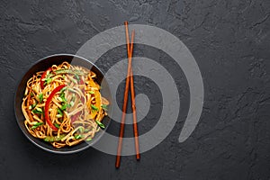 Vegetarian Schezwan Noodles or Vegetable Hakka Noodles or Chow Mein in black bowl at dark background. Indo-chinese cuisine hot