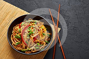 Vegetarian Schezwan Noodles or Vegetable Hakka Noodles or Chow Mein in black bowl at dark background. Indo-chinese cuisine hot