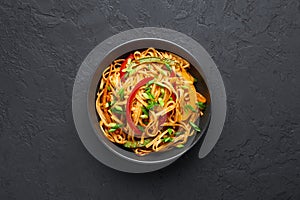Vegetarian Schezwan Noodles or Vegetable Hakka Noodles or Chow Mein in black bowl at dark background. Schezwan Noodles is indo-