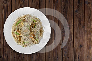 Vegetarian Schezwan Noodles or Vegetable Hakka Noodles or Chow Mein in white plate at wooden background. Schezwan Noodles is indo-