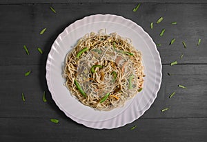 Vegetarian Schezwan Noodles or Vegetable Hakka Noodles or Chow Mein in white plate at wooden background. Schezwan Noodles is indo-