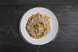 Vegetarian Schezwan Noodles or Vegetable Hakka Noodles or Chow Mein in white plate at wooden background. Schezwan Noodles is indo-