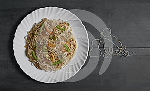 Vegetarian Schezwan Noodles or Vegetable Hakka Noodles or Chow Mein in white plate at wooden background. Schezwan Noodles is indo-