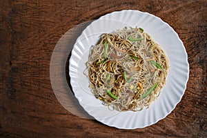 Vegetarian Schezwan Noodles or Vegetable Hakka Noodles or Chow Mein in white plate at wooden background. Schezwan Noodles is indo-