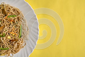 Vegetarian Schezwan Noodles or Vegetable Hakka Noodles or Chow Mein in white plate at wooden background. Schezwan Noodles is indo-