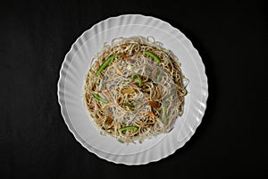 Vegetarian Schezwan Noodles or Vegetable Hakka Noodles or Chow Mein in white plate at wooden background. Schezwan Noodles is indo-