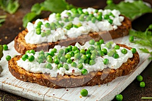 Vegetarian seeded sourdough bread open sandwich with cottage cheese and petit poit peas sprinkled with chilli flakes