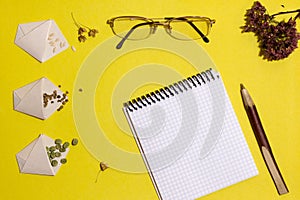 Vegetarian seeds in handmade bags, notebook, pen, glasses on a yellow background. View from above. Place for an inscription.