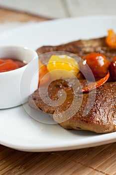 Vegetarian steak made from vegan meat seitan, with cherry tomatoes