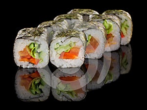 Vegetarian Sushi roll with vegetables: pepper, cucumber, avocado and salad isolated on black background with reflection