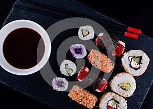 Vegetarian sushi set  with chopsticks and soy on a black plate on black background