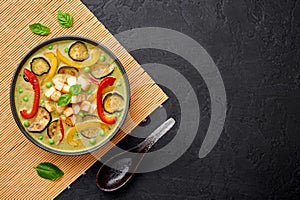 Vegetarian Thai Green Curry with tofu in black bowl at dark slate background. Thailand cuisine dish. Thai Food