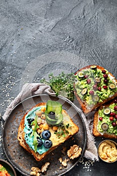 Vegetarian toasts with hummus, blueberry, avocado, tomato. delicious vegan breakfast on dark background