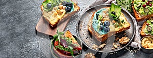 Vegetarian toasts with hummus, blueberry, avocado, tomato. delicious vegan breakfast on dark background
