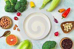 Vegetarian and vegan healthy lifestyle concept. Raw vegetables and fruits with empty plate over rustic background. Top view, flat