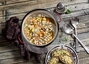 Vegetarian vegetable bean soup and parmesan cheese toasts on a wooden rustic table, top view.