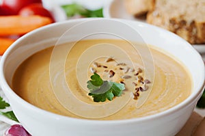Vegetarian vegetable cream soup with eggplant and carrots in white bowl on wooden table