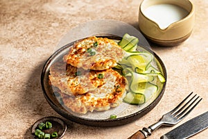 Vegetarian zucchini pancakes served with cucumber and cream sauce on brown background with cutlery