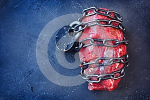 Vegetarianism. Vegan food concept with piece of meat, metallic chain and lock.