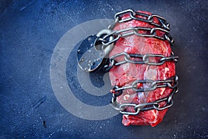 Vegetarianism. Vegan food concept with piece of meat, metallic chain and lock. photo