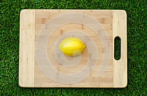 Vegetarians and cooking on the nature of the theme: lying on a cutting board and knife lemon yellow on the background of grass