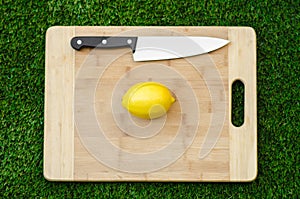 Vegetarians and cooking on the nature of the theme: lying on a cutting board and knife lemon yellow on the background of grass