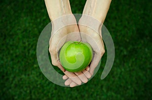 Vegetarians and fresh fruit and vegetables on the nature of the theme: human hand holding a green apple on a background of green g